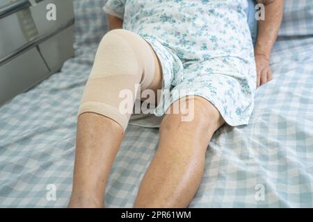 Donna anziana asiatica anziana o anziana paziente con supporto ginocchio dolore articolare a letto in reparto ospedale infermieristico, sano forte concetto medico. Foto Stock