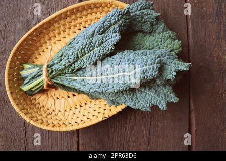 Foglie fresche di cavolo nero su sfondo di legno. Black Kale. Cucina italiana. Fase di cottura per mangiare sano, pronto a preparare cibo vegetariano Foto Stock