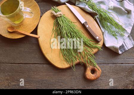 Pianta di Horsetail fresco su un tavolo con tè alle erbe sullo sfondo di legno Foto Stock