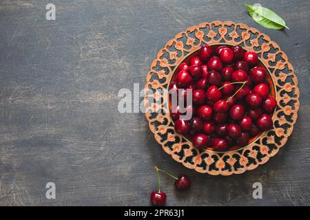 Composizione delle ciliegie dolci su un piatto con gocce d'acqua. Concetto di estate e raccolto. Ciliegio macro. Vegano, vegetariano, crudo Foto Stock
