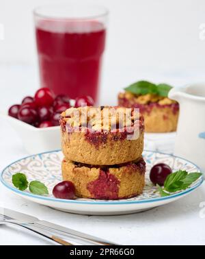 Torta crumble di ciliegia porzionata su un piatto, sfondo bianco Foto Stock