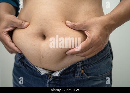 Il sovrappeso donna asiatica mostrano il grasso ventre presso l'ufficio. Foto Stock