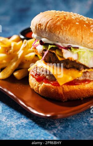 Hamburger. Succulenti cotolette di maiale, formaggio cheddar, cipolle croccanti sottaceto, lattuga avvolta in un panino sotto due salse. Servito con patatine fritte e salsa alla panna. Foto Stock