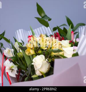 Primo piano di un bouquet di fiori colorati avvolti in carta regalo. Foto Stock