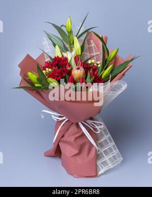 Bouquet di fiori confezionati in un involucro bianco-rosa si staglia su uno sfondo blu. Foto Stock