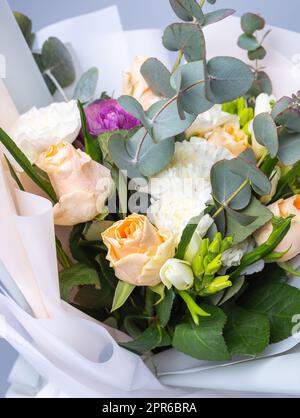 Primo piano di un bouquet di rose, peonie e ramoscelli di eucalipto su sfondo blu. Foto Stock