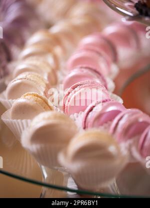 Macaron freschi, appetitosi, dolci, di rosa, cremosi e viola si chiudono su un tavolo a buffet decorato Foto Stock