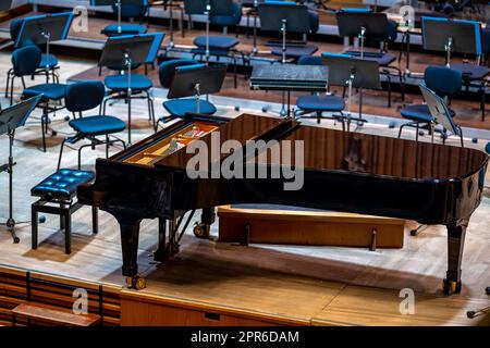 Un pianoforte sul palco della Filarmonica tra gli altri strumenti musicali Foto Stock