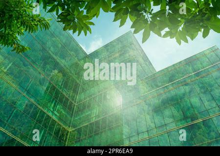 Edificio ecologico nella città moderna. Edificio sostenibile in vetro per uffici con alberi per ridurre il calore e l'anidride carbonica. Edificio di uffici con ambiente verde. Riduzione degli edifici aziendali CO2. Foto Stock