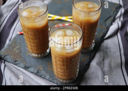 D'estate, sorseggiate un caffè ghiacciato in un bicchiere alto su un rustico sfondo di legno. Messa a fuoco selettiva Foto Stock