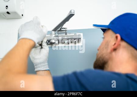 Tuttofare installazione e fissaggio del chiudiporta automatico Foto Stock