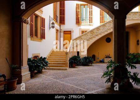 Palma, Mallorca - 5 agosto 2019 : Scale in un cortile visto attraverso un arco in un edificio storico nel centro storico di Palma de Mallorca Foto Stock