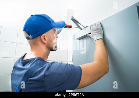 Tuttofare installazione e fissaggio del chiudiporta automatico Foto Stock