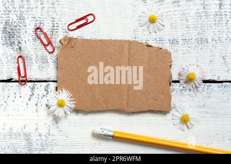 Frammento di carta con messaggio importante con matita, fiori e graffette intorno. Cartoncino strappato con informazioni Crutial con clip su tutto il pavimento. Foto Stock