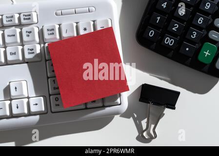 Messaggi importanti scritti sulla nota sulla scrivania con calcolatrice, graffetta e tastiera. Informazioni Crutial presentate su Memo su Office Table. Annunci recenti visualizzati. Foto Stock