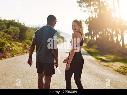 Il mio ragazzo fa il migliore compagno di allenamento. Scatto di una giovane coppia in forma che rallenta per una passeggiata durante la loro corsa all'aperto. Foto Stock