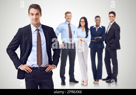Unità attraverso la diversità aziendale. Studio girato di un uomo d'affari con le mani sui fianchi in piedi davanti ai suoi colleghi. Foto Stock