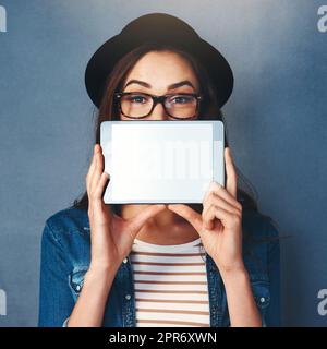 Ho l'app per te. Scatto di una ragazza attraente che tiene il tablet davanti al suo volto in studio. Foto Stock