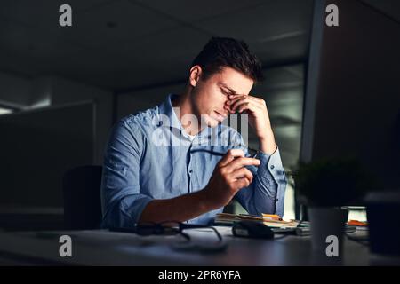 Mettendo in quelle ore di straordinario. Scatto di un giovane uomo d'affari che lavora a tarda notte in un ufficio moderno. Foto Stock