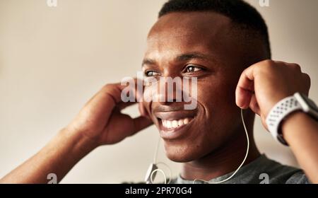 Nessuno mi motiva come la musica. Scatto corto di un bel giovane uomo che gli mette le cuffie nelle orecchie. Foto Stock