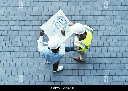 Condividere le sue idee e la sua visione. Scatto ad alta angolazione di due ingegneri che guardano un progetto. Foto Stock