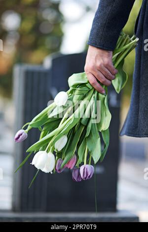 Andato ma non dimenticato. Scatto corto di un uomo che visita un cimitero con un mazzo di fiori. Foto Stock