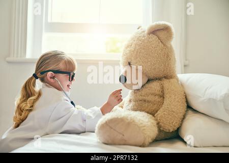 Thats un buon cuore che avete là, teddy. Girato di una bambina adorabile vestita come medico ed esaminando un orsacchiotto con uno stetoscopio. Foto Stock