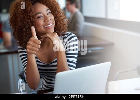 Youve ha ottenuto il suo sigillo di approvazione. Ritratto di una giovane donna che vampata e che dà i pollici in su mentre si siede in un ufficio. Foto Stock