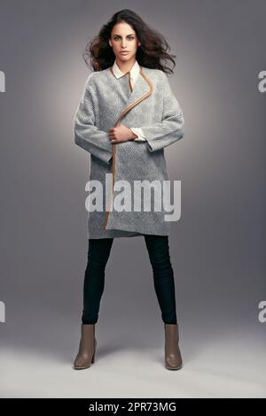 Incredibile in inverno couture. Studio girato di una giovane donna vestita elegantemente su sfondo grigio. Foto Stock