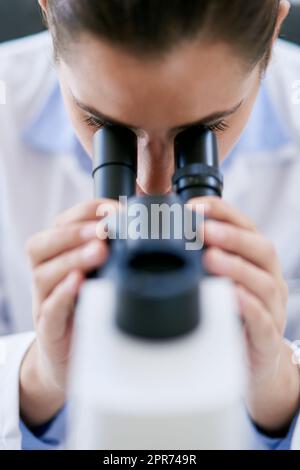 Theres sempre qualcosa di nuovo da scoprire. Scatto corto di una giovane scienziata femminile utilizzando un microscopio in un laboratorio. Foto Stock