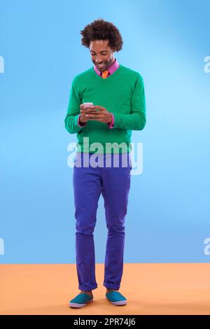 L'aggiornamento dello stato è stato molto gradevole. Studio di giovane uomo elegante che parla al telefono su uno sfondo colorato. Foto Stock