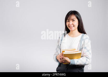 Donna giovane sorridente tenendo e abbracciare abbracciare il libro preferito per l'amante Foto Stock