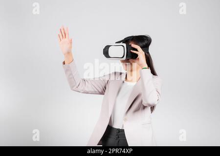 Donna sorridente fidata, indossa il visore VR che tocca l'aria durante l'esperienza di realtà virtuale Foto Stock