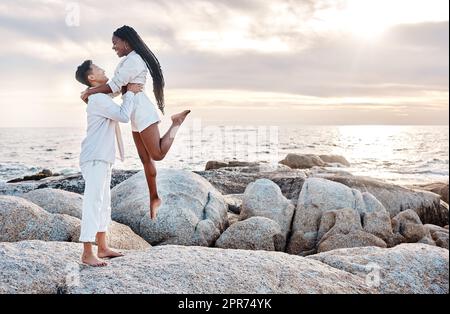 Una giovane coppia di gare miste che si gode una giornata in spiaggia, con un aspetto felice e innamorato. Una giovane coppia di gare miste che si gode una giornata in spiaggia, con un aspetto felice e innamorato. Foto Stock