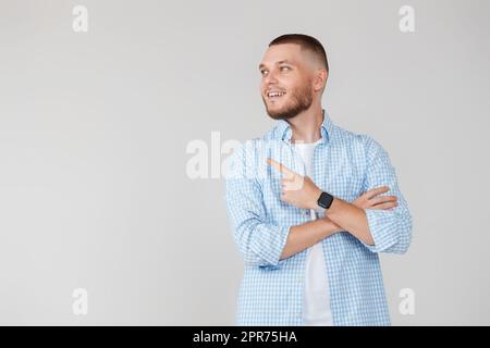 Il giovane bel barbuto uomo che punta verso il lato Foto Stock