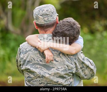 Le lacrime fluiscono dagli occhi dei cari. Fucilato di un padre che ritorna dall'esercito abbracciando il figlio fuori. Foto Stock