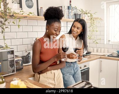 Divertimento con un amico. Shot di due giovani amici che bevono vino insieme a casa. Foto Stock