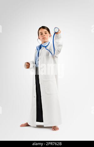 Sognate il piccolo grande. Studio girato di una bambina adorabile vestirsi come medico. Foto Stock