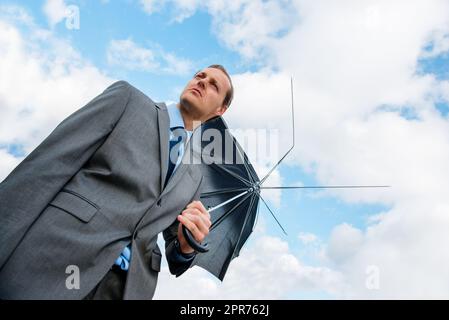 Nessuna copertura in vista per lui. Colpo di un uomo d'affari che tiene un ombrello rotto. Foto Stock