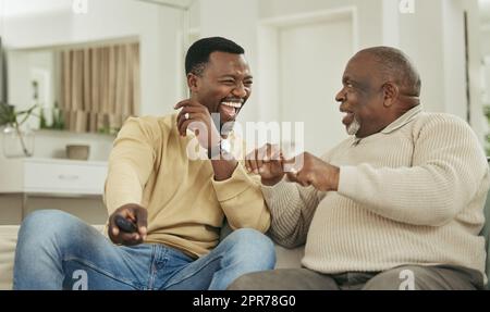 Una famiglia felice è solo un cielo più vecchio. Scatto di un padre e di un figlio che ridono nel salotto. Foto Stock