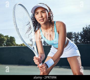 Non salterò mai un giorno per allenarmi. Scatto di una giovane donna attraente in piedi da sola e prepararsi a colpire la palla durante una partita di tennis. Foto Stock