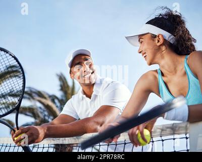 Erano un potente duo. Tiro di due giocatori di tennis in piedi insieme e appoggiati in rete durante la pratica. Foto Stock