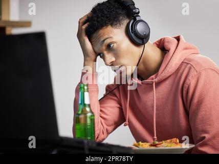 Perché questo gioco continua a rimanere in ritardo. Scatto di un giovane che guarda turbato mentre gioca ai videogiochi a casa. Foto Stock