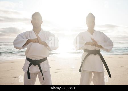 Shoiwng rispetto. Scatto corto di due giovani artisti marziali che praticano il karate sulla spiaggia. Foto Stock