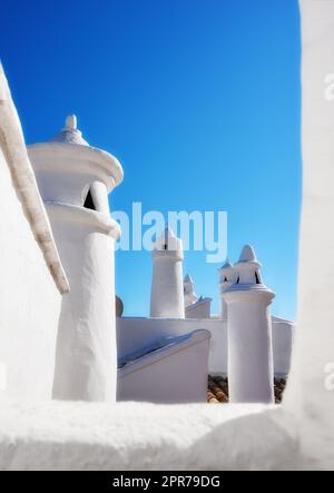 Storico camino di ventilazione sul tetto di un edificio d'epoca. Sistema di aerazione di architettura tradizionale in un villaggio. Vista esterna di una casa rurale o di una casa sul tetto isolata su uno sfondo blu del cielo Foto Stock