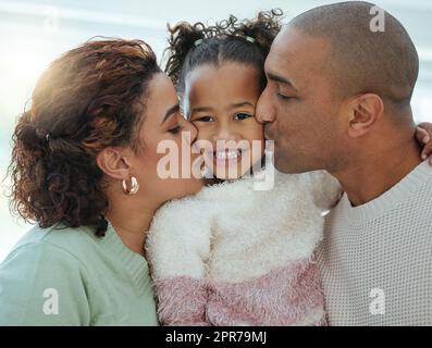 Le parole possono persino descrivere quanto amo i miei genitori. Una bambina adorabile che ottiene baci sulle sue guance dai suoi genitori. Foto Stock