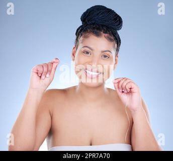 Il flossing è un investimento. Studio ritratto di una giovane donna attraente che galleggiava i denti su uno sfondo blu. Foto Stock