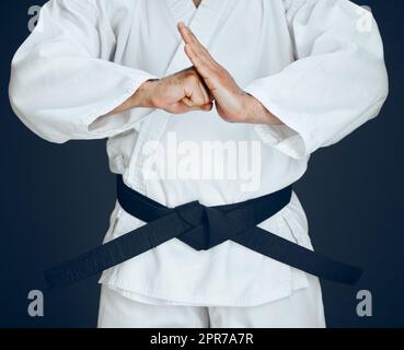 Il relativo circa onore. Un artista marziale maschio irriconoscibile che pratica il karate in studio su uno sfondo scuro. Foto Stock