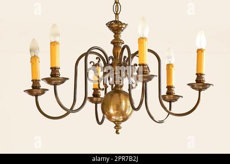 Eleganti luci a sospensione vintage per un grande atrio o una sala da pranzo. Oggetto d'illuminazione a forma di candela dorata per interni dal design in stile vittoriano reale. Lampadario in ottone appeso a molte lampadine. Foto Stock