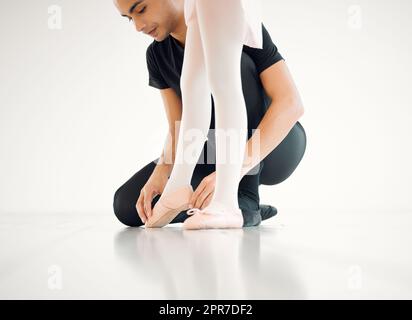 Posizionare i piedi in questo modo. Primo piano di un insegnante di balletto che assiste uno studente con la sua posizione in uno studio di danza. Foto Stock